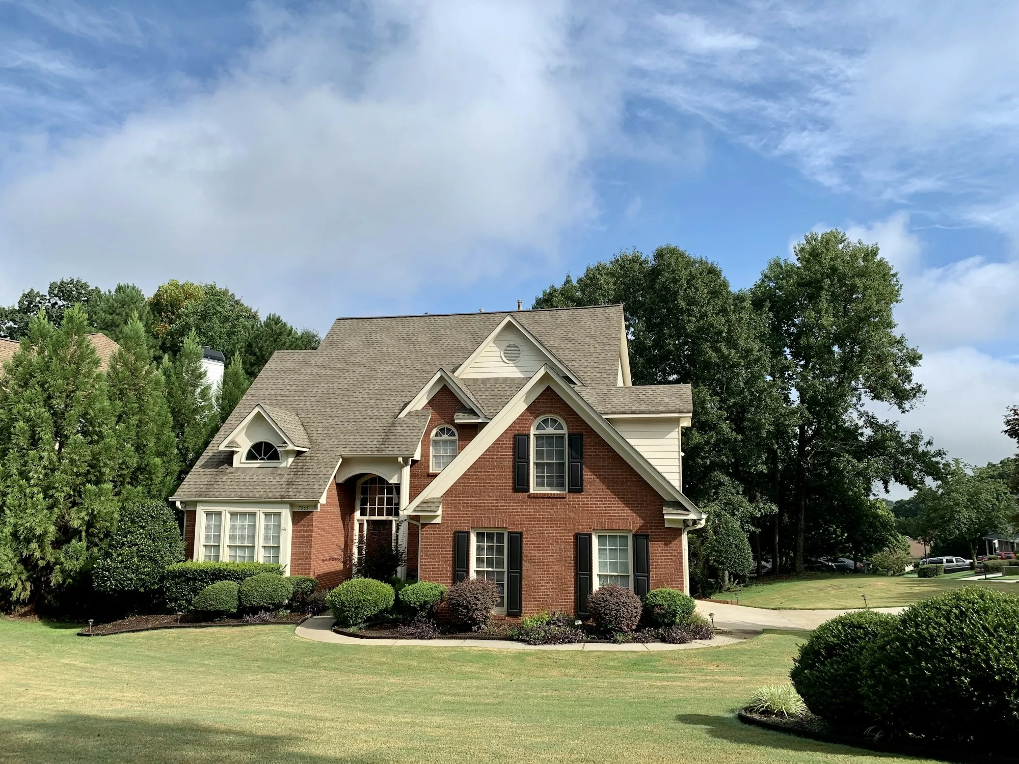 Brick suburban home surrounded by trees